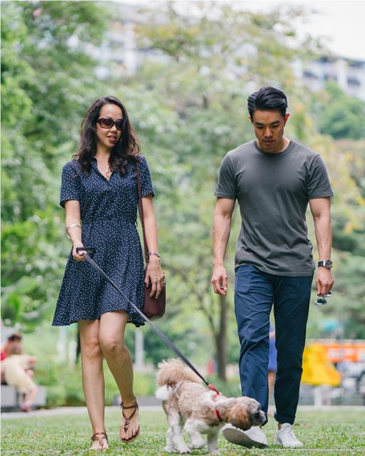 A couple out on a-walk with their dog who is sniffing around
